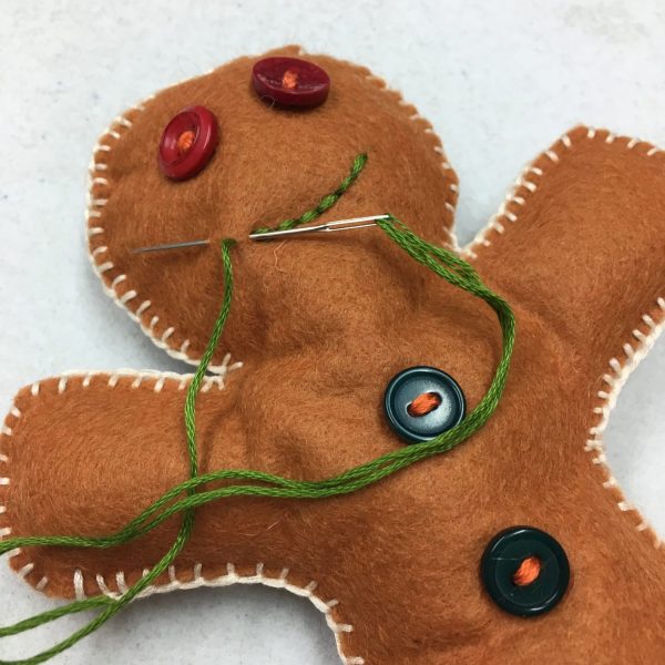 Kids hand sewing gingerbread man